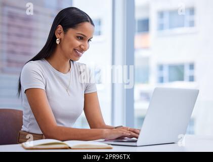 Lavorare diligentemente. Una giovane donna d'affari attraente che lavora sul suo laptop mentre si siede in ufficio. Foto Stock