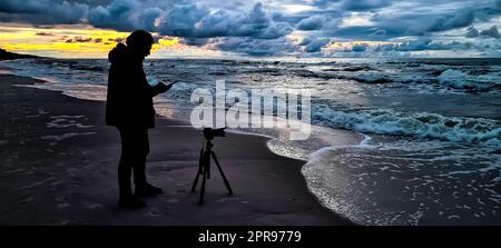 Tramonto sul Mar Baltico con fotografo e piattaforma petrolifera sullo sfondo: Lubiatowo, Pomerania, Polonia Foto Stock