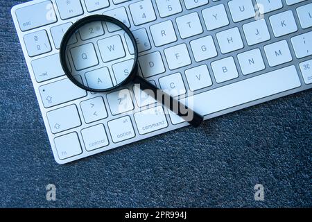 Lente di ingrandimento e tastiera del computer portatile. SEO, ricerca di dati nella rete. Chat GPT. Trasformazione digitale. Foto Stock