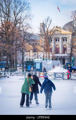 Tre bambini pattinano sul ghiaccio in inverno di fronte al castello del palazzo reale di Oslo, Norvegia Foto Stock