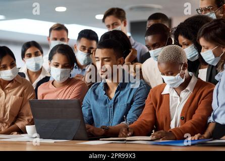 Rendetela ancora migliore la prossima volta. Un gruppo di giovani uomini d'affari che utilizzano un notebook in una conferenza in un ufficio moderno. Foto Stock