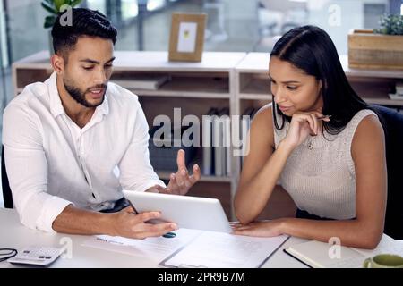 Due sono le menti migliori di una: Due colleghi lavorano insieme utilizzando un tablet digitale. Foto Stock