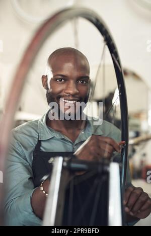 Im il parlò re, un bel giovane uomo che si levò in piedi da solo nel suo negozio e riparò una ruota di bicicletta. Foto Stock