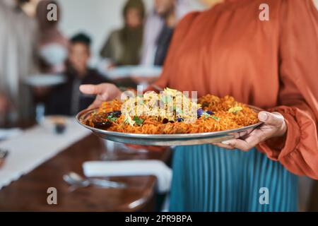 Questo è il mio piatto preferito: Una donna musulmana che tiene un piatto di cibo. Foto Stock