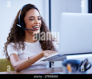 Il gioco delle vendite è sempre al top. Un giovane agente di call center che lavora su un notebook in ufficio. Foto Stock