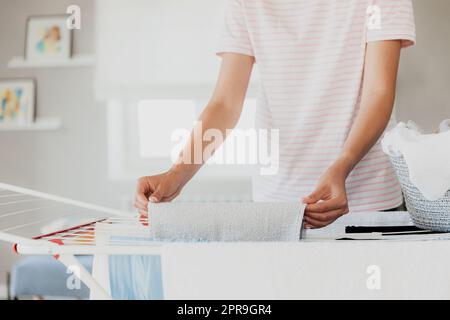 Donna che appende i capi puliti e bagnati sul piano di asciugatura nella lavanderia di casa Foto Stock