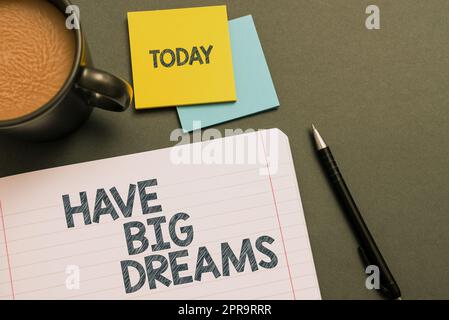 Il cartello di testo mostra i grandi sogni. Ispirazione per il concetto di business per immaginare un grande futuro obiettivi di sviluppo notebook con messaggio importante sulla scrivania con caffè, penna e note. Foto Stock