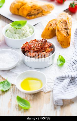 Pomodoro essiccato al sole con olio d'oliva come antipasto con avocado spalmato e baguette Foto Stock