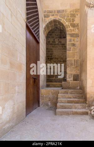 Scalinata in pietra che porta all'ingresso a volta presso il muro di pietra in mattoni Foto Stock