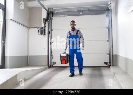 Installazione e riparazione della porta del garage a casa. Uomo appaltatore Foto Stock