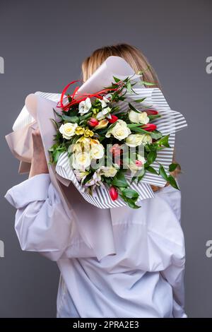 La donna sta in piedi con la schiena alla telecamera e tiene sulle spalle un bouquet. Foto Stock