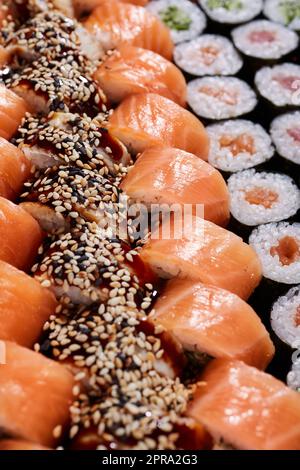 Set grande con file di diversi tipi di sushi roll con ripieni diversi. Foto Stock