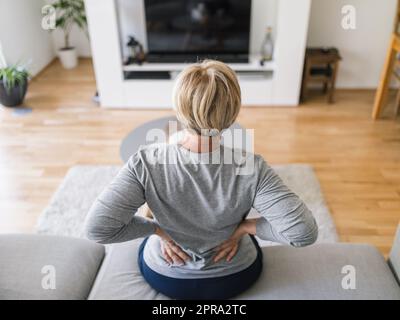 Donna anziana a casa con mal di schiena Foto Stock