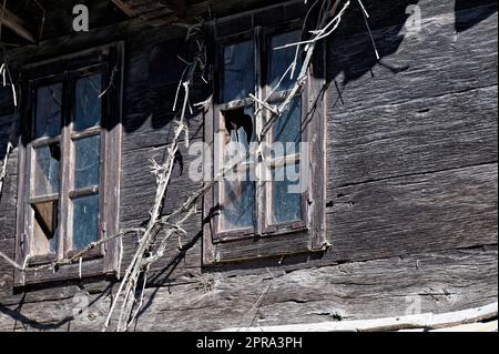 Vecchia casa di legno con finestre rotte Foto Stock