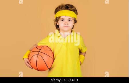 Stile di vita sportivo attivo. Carino bambino in abbigliamento sportivo con palla da basket. Piccolo basketballer. Attrezzature sportive. Gioco di allenamento di basket. Infanzia e. Foto Stock