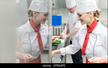 Chef in una grande cucina commerciale che cucinano i pasti insieme Foto Stock