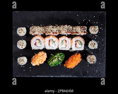 Vista dall'alto, vari tipi di sushi serviti su uno sfondo scuro. Festa asiatica del cibo. Foto Stock