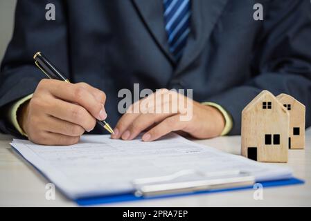 Mano d'affari che tiene la penna segno contratto documento di carico di proprietà house.Business finanza investimento assicurazione e concetto di imposta. Foto Stock
