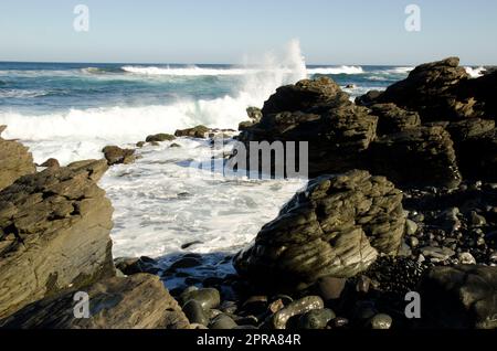 Onde che si infrangono contro le rocce. Foto Stock