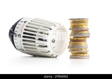 Testa della valvola termostatica con monete isolate su sfondo bianco. Foto Stock
