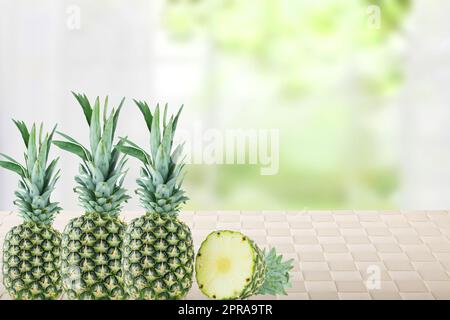 Frutti di ananas freschi maturi su un tavolo su uno sfondo astratto sfocato e luminoso delle finestre naturali. Nutrizione sana. Frutta tropicale o concetto sanitario. Spazio per il design. Foto Stock