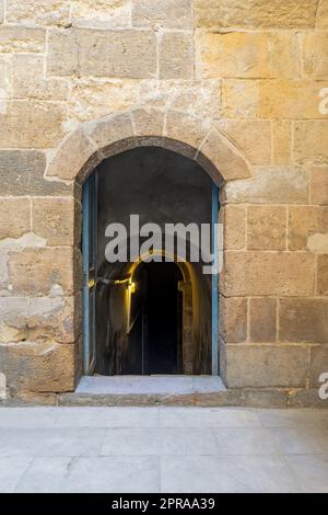 Muro in mattoni di pietra con porta in legno che conduce alla cisterna d'acqua che giace sotto il complesso di El Silahdar, il Cairo Foto Stock