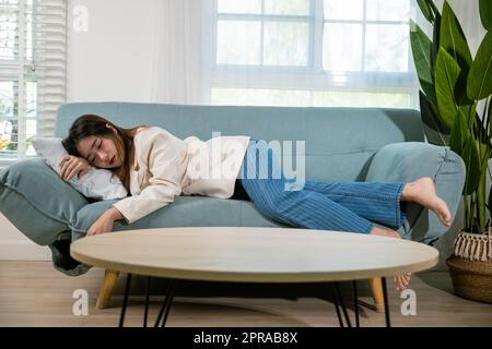 Donna stanca che dorme a occhi chiusi sul divano in soggiorno Foto Stock