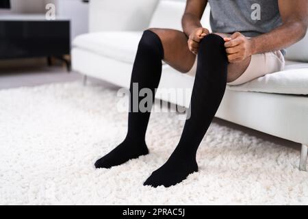 Uomo che mette sulle calze mediche di compressione Foto Stock
