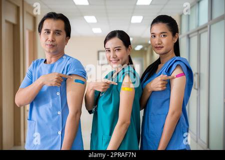 Personale medico che indica la benda con intonaco sul braccio dopo aver ottenuto contro il vaccino Covid-19 Foto Stock