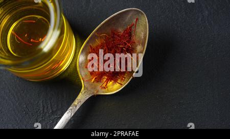 Costosa spezia di zafferano rossa secca in un cucchiaio su fondo scuro Foto Stock