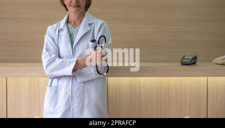 Medico femminile in possesso di stetoscopio e braccia incrociate in ospedale. Foto Stock
