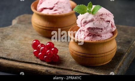 Misurini rosa di pistole con ribes rosso su un tavolo nero. Gelato Foto Stock