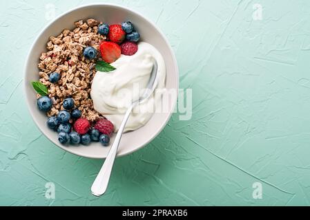 Un piatto di granola secca servito con frutta fresca alla bacche e yogurt. Piastra di farina d'avena. Cibo sano, dieta. Vista dall'alto. Foto Stock