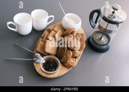 Un gustoso spuntino, due tazze di tè nero e un piatto di biscotti alla farina d'avena, una tavola di legno su sfondo grigio, tè alle foglie. Foto Stock