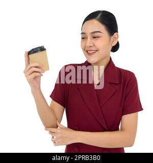 Giovane donna d'affari asiatica in abito rosso con un sorriso che tiene una tazza di caffè. Ritratto su sfondo bianco con luce da studio. Foto Stock