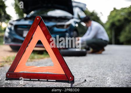 L'uomo d'affari asiatico auto rotta ha problemi con la ruota della sua auto Foto Stock