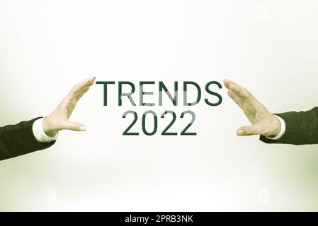 Segno di testo che mostra i trend 2022. Internet Concept il prossimo anno prevalente tendenza ampiamente discussa Online informazioni importanti presentate tra le mani del team aziendale. Foto Stock