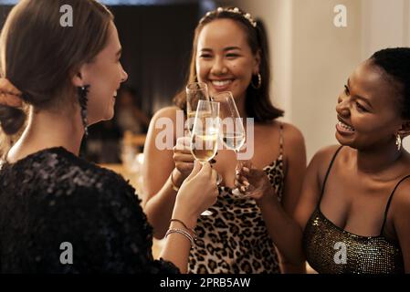 Che il nuovo anno ci porti tante avventure. Un gruppo eterogeneo di amici in piedi e brindando con champagne durante una cena di Capodanno. Foto Stock