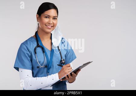 Quando il medico è carino, dimentica la frutta. Ritratto di un giovane medico che indossa uno stetoscopio e prende appunti su una clipboard su uno sfondo bianco. Foto Stock