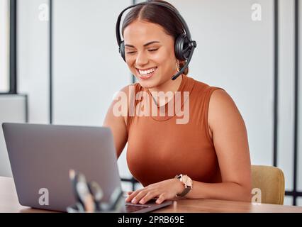 Shes sempre così felice di aiutare. Una giovane e attraente agente di call center femminile che lavora sul suo laptop. Foto Stock