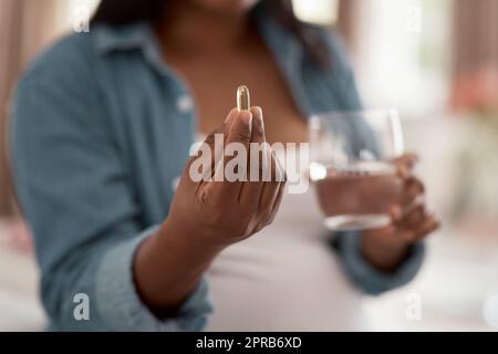 Questo supplemento aiuta con una gravidanza sana. Primo piano di una donna incinta che assume farmaci a casa. Foto Stock