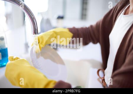 A nessuno piace una cucina sporca, una donna irriconoscibile che lava i piatti a casa. Foto Stock