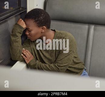 Sentendosi giù ed fuori. Scatto ad angolo alto di una giovane donna che guarda depressa mentre viaggia in treno. Foto Stock
