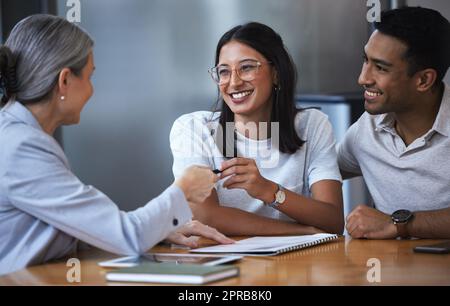 Youre mio, il suo nostro. Una giovane coppia incontro con un consulente per discutere di documenti un ufficio. Foto Stock