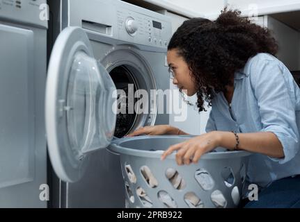 La lavanderia fresca ha sempre un ottimo odore, una giovane donna che si prepara a lavare un carico di lavanderia a casa. Foto Stock