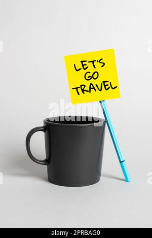 Cartello di testo che mostra Let S è Go Travel. Internet Concept pianificare un viaggio visitare nuovi luoghi paesi città avventura Cup, penna e nota adesiva con annuncio importante alla scrivania. Foto Stock