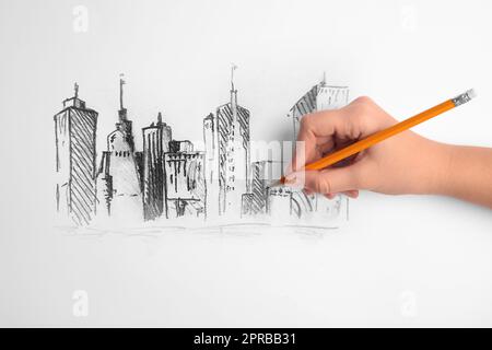 Donna disegno schizzo del paesaggio urbano con matita di grafite su carta bianca, primo piano Foto Stock