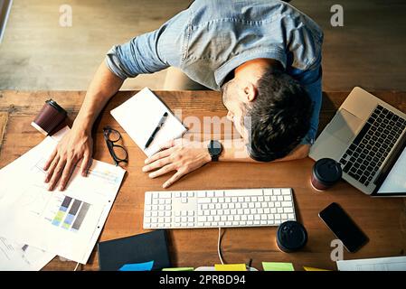 Si spinse oltre il suo limite. Shot di un giovane uomo d'affari esausto che dorme alla sua scrivania durante una notte tarda al lavoro. Foto Stock