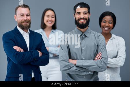 Theres niente che abbatte una squadra così forte. Ritratto di un gruppo di uomini d'affari in piedi insieme su uno sfondo grigio. Foto Stock