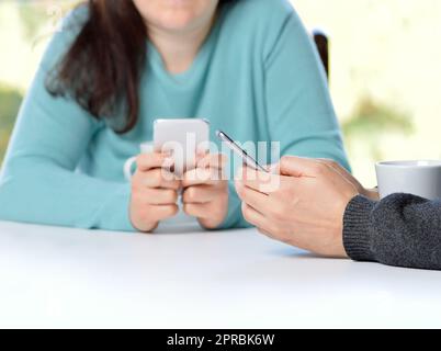 Due amici che usano i loro smartphone in un bar Foto Stock